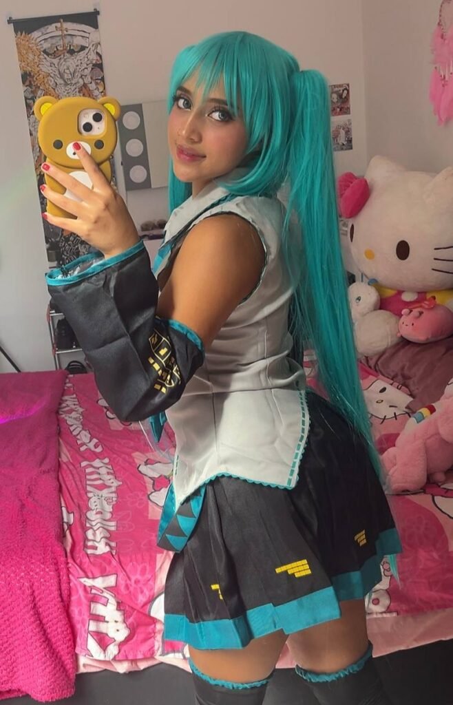 Ele Villa in cosplay di Hatsune Miku con parrucca turchese e posa davanti allo specchio
